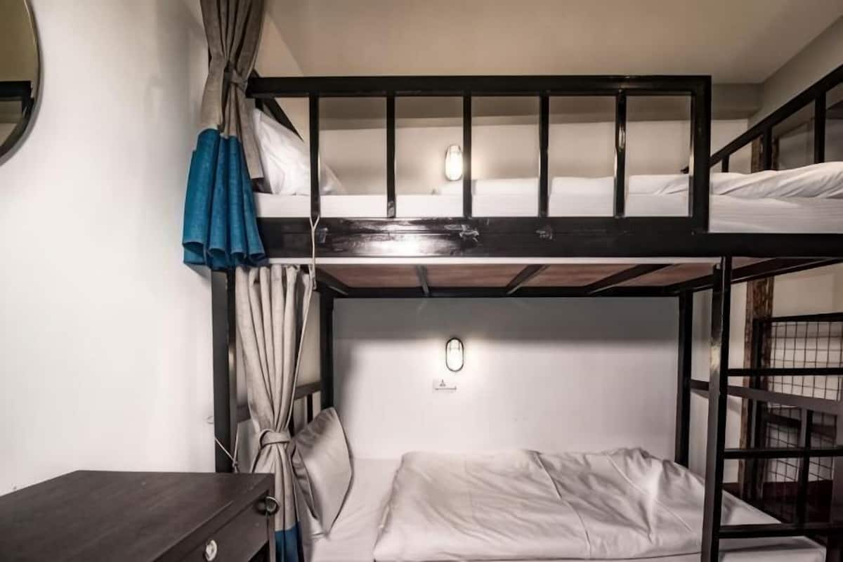 A bunk bed room with a desk and a curtain.