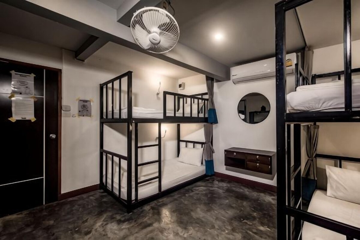 A bunk bed room with a ceiling fan, a door with a notice, and a circular wall decoration.