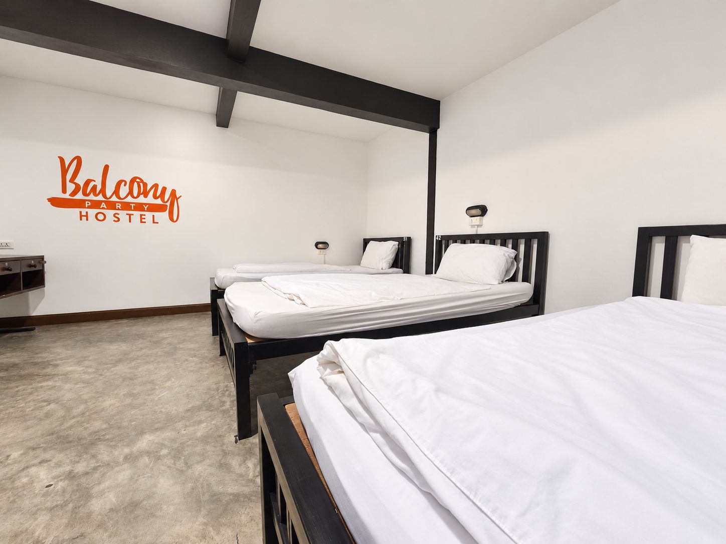 Ein Hotelzimmer mit zwei Betten, einer Wandleuchte und einem Schild mit der Aufschrift 'Balcony Party Hostel'.
