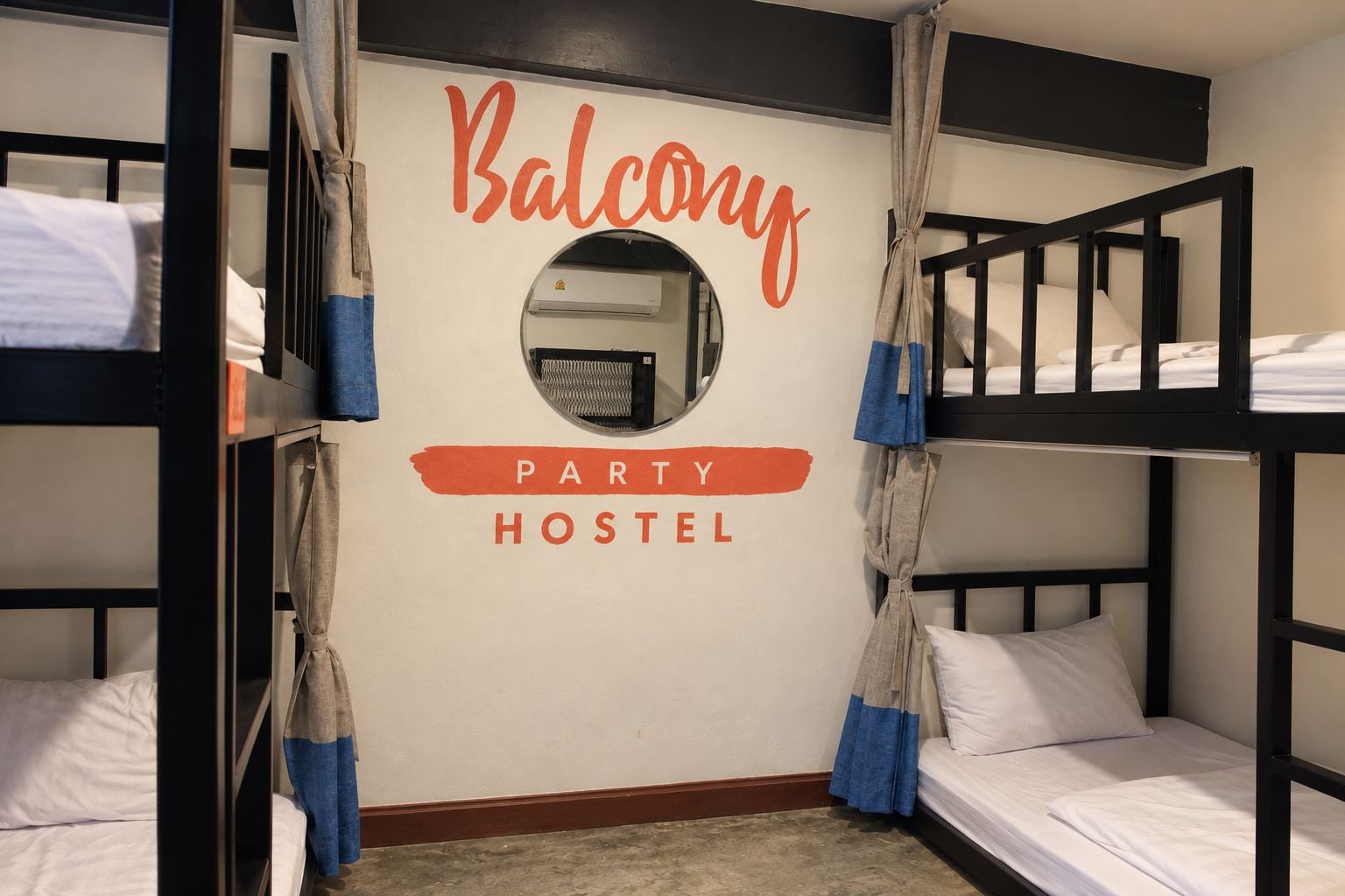 Habitación de hostal con literas, un espejo y un cartel en la pared que indica que es un hostal para fiestas.