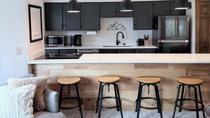 A modern kitchen with dark cabinets, a stainless steel refrigerator, a microwave, and a coffee maker. There are three stools and a wooden bar counter. - REMODELED Cozy Mountain Modern Ski-in 1 block to Heart of Breckenridge
Hot Tubs (Breckenridge)