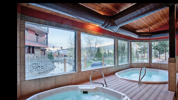 A spa area with two hot tubs and large windows offering views of a building and trees. - REMODELED Cozy Mountain Modern Ski-in 1 block to Heart of Breckenridge
Hot Tubs (Breckenridge)