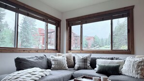 A modern living room with a grey sectional sofa, multiple pillows, a white throw blanket, and a tray with two mugs. Large windows offer a view of buildings and trees. - REMODELED Cozy Mountain Modern Ski-in 1 block to Heart of Breckenridge
Hot Tubs (Breckenridge)