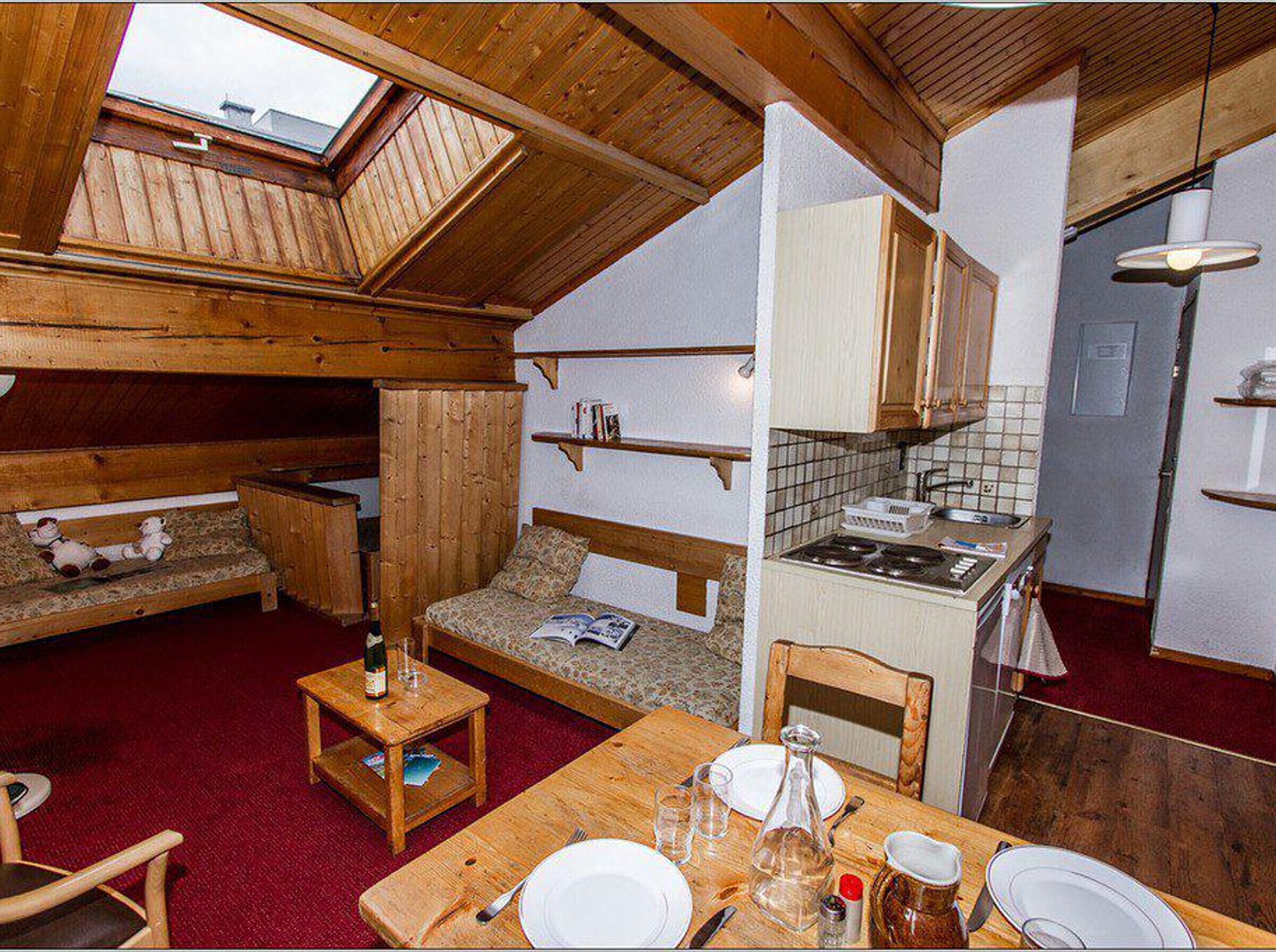 A compact, rustic cabin with a loft bedroom, a kitchenette, and a dining area.