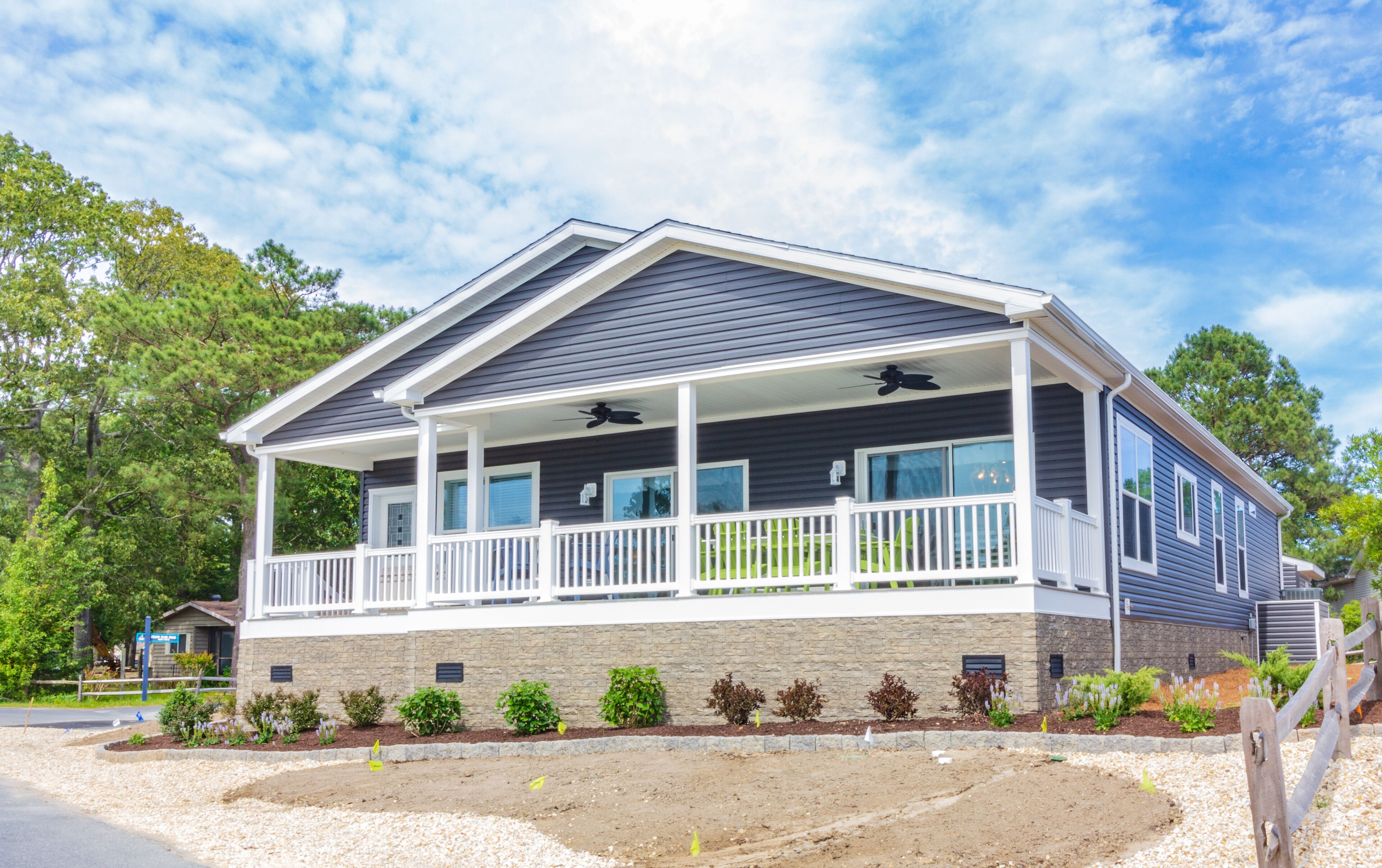 A two-story house with a covered porch, a stone foundation, and a landscaped front yard.