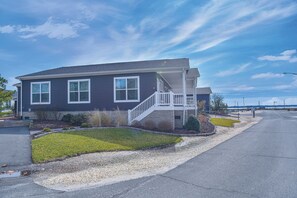 A two-story house with a front porch and a small front yard. - Family fun-large home, beach, pools, pet friendly! (Long Neck)