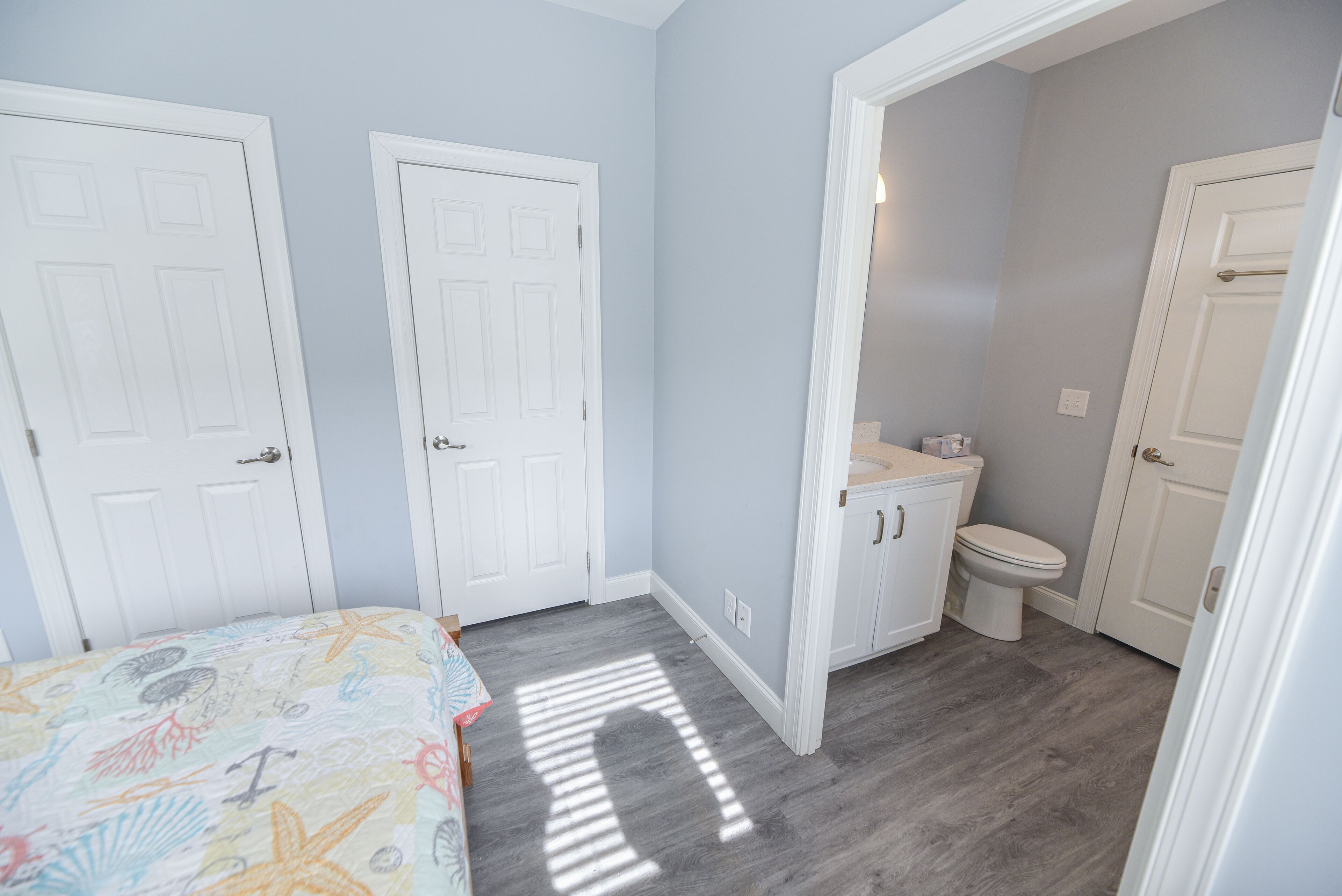 A bedroom with a bed, a bathroom with a toilet and sink, and a hallway.