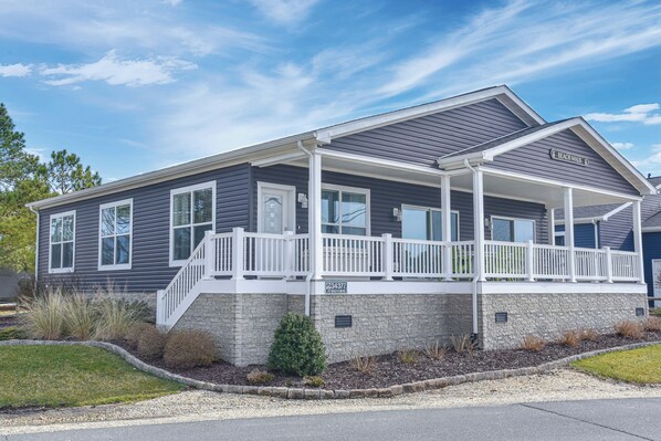 A two-story house with a covered porch, a stone foundation, and a sign indicating 'Beach Walk'. - Family fun-large home, beach, pools, pet friendly! (Long Neck)
