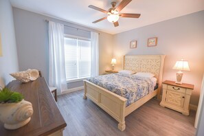 A bedroom with a bed, bedside tables, a ceiling fan, a window with curtains, and a wooden floor. - Family fun-large home, beach, pools, pet friendly! (Long Neck)