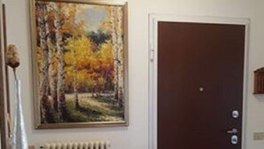 A room with a radiator, a door, and a painting of a forest scene.