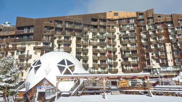 A multi-story hotel with balconies, a large dome structure in front, and signs for a restaurant and snack bar.