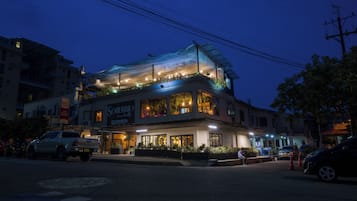 Ein Hotel mit Dachterrasse, mehreren Etagen und einer gut beleuchteten Fassade.