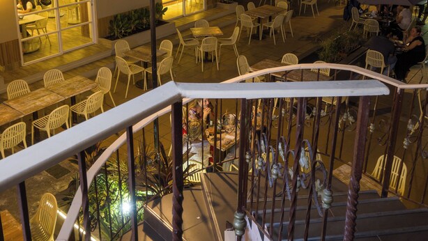 A rooftop terrace with outdoor seating, a staircase, and a bar area.