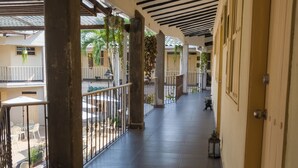 A corridor with tiled flooring, black ceiling beams, and a door on the right.
