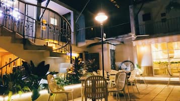 A well-lit outdoor patio area with a spiral staircase, outdoor seating, and a large wheel chair.