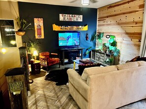 Un salon équipé d’un téléviseur, de lambris en bois, d’un canapé, d’un fauteuil et de divers éléments de décoration.
