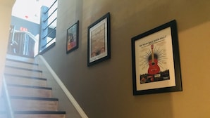 Een trap met een lijst met een poster van een gitaar en tekst op de muur.