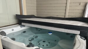 Un bain à remous doté d’une couverture noire, d’un panneau de commande et d’un drain.
