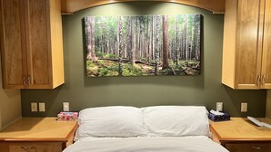Une chambre à coucher avec un lit, des armoires en bois et une décoration murale sur le thème de la forêt.