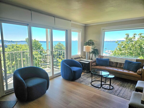 Ein ger äumiger Balkon mit Blick aufs Wasser, ausgestattet mit einer Couch, Stühlen und einem kleinen Tisch.
