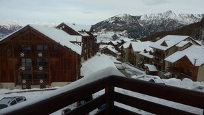 A snow-covered mountain village with wooden buildings and a view of snow-capped mountains. - Luxury apartment in Les Orres 1800 with pool, sauna, hammam, and WiFi (Les Orres)