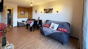 A cozy living room with a sofa, a dining table, and a kitchen area. - Luxury apartment in Les Orres 1800 with pool, sauna, hammam, and WiFi (Les Orres)