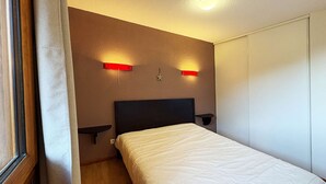 A hotel room with a bed, bedside tables, and a wardrobe. - Luxury apartment in Les Orres 1800 with pool, sauna, hammam, and WiFi (Les Orres)
