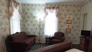 Una habitación con una cama, un sofá, una silla, un escritorio y una televisión.