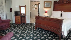 Un dormitorio con una cama de madera, un aparador, un televisor y una silla.