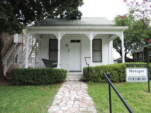 A white house with a stone pathway leading to the front door. There is a sign indicating 'Metzger Sunday House' with a phone number.