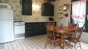 Una cocina con una mesa de comedor y sillas, un refrigerador, estufa y alacenas.