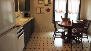 Una cocina con una mesa de comedor y sillas, un refrigerador y una estufa.