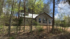 A two-story house surrounded by dense forest.