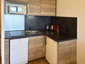 Cozinha compacta com lava-louças, pia, torradeira e cafeteira.
