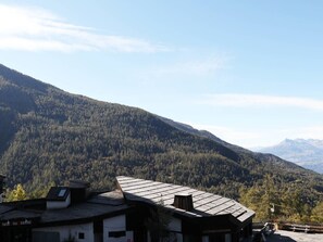 A mountain landscape with a building featuring a sloped roof and a sign that reads "les Ecrins".