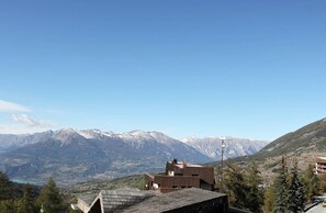 A mountain view with a wooden building in the foreground and snow-capped mountains in the background.