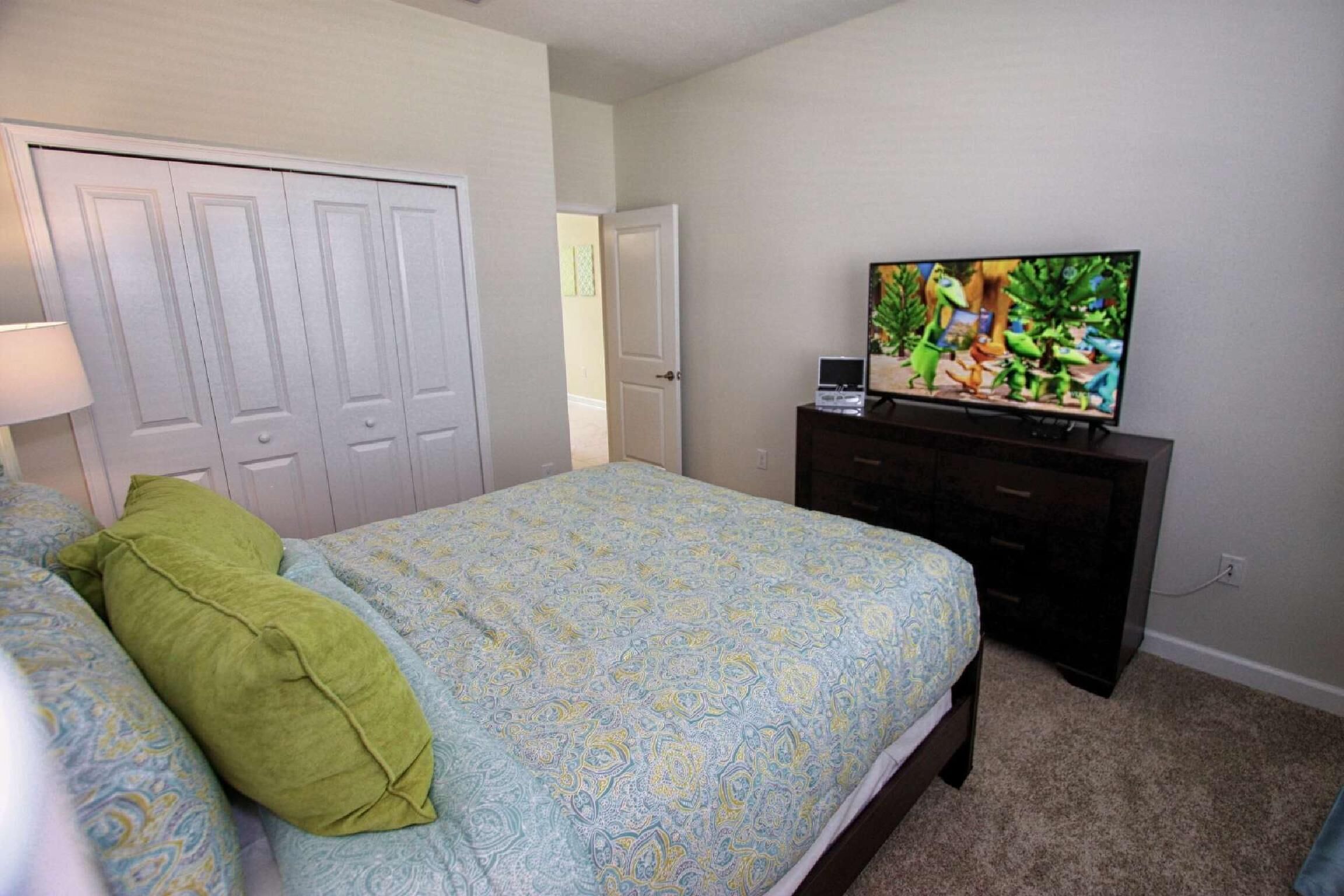 Un dormitorio con cama, cómoda, televisor y armario.