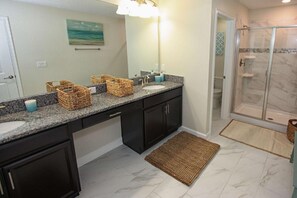 A bathroom with dark cabinets, a granite countertop, a white sink, and a glass shower enclosure. - 1620 Champions Gate (Davenport)