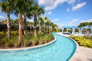 A curved swimming pool with a blue border, surrounded by palm trees and a gazebo. - 9039 Windsor at Westside (Kissimmee)