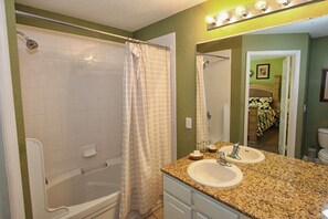 Ein Badezimmer mit Badewanne, Duschvorhang, Waschbecken und Waschtisch.