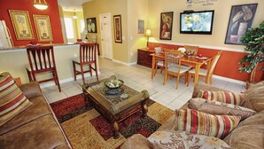 A living room with a sofa, a coffee table, and a dining area with chairs and a table. - 2582 Windsor Hills (Kissimmee)