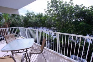 A balcony with a table and chairs, white railing, and a view of trees and water. - 456 Little Harbor (Ruskin)