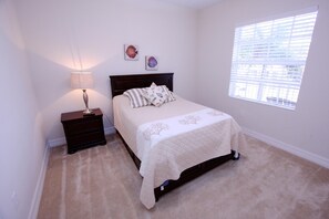 A bedroom with a bed, nightstand, lamp, and window. - 456 Little Harbor (Ruskin)