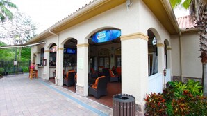 An outdoor seating area with a Bud Light sign, outdoor bar, and a trash can. - 1361 Tuscana (Davenport)