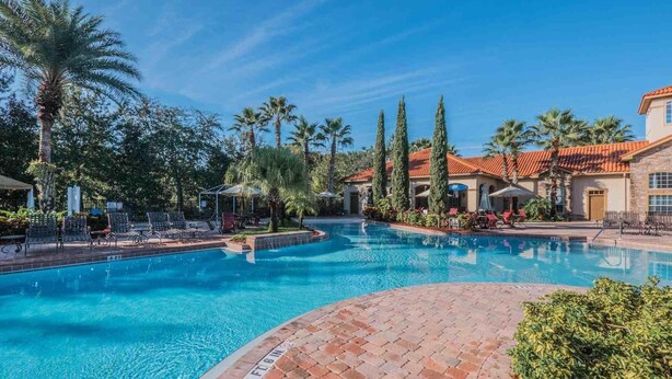 A swimming pool with a brick border, surrounded by palm trees and lounge chairs. - 1361 Tuscana (Davenport)