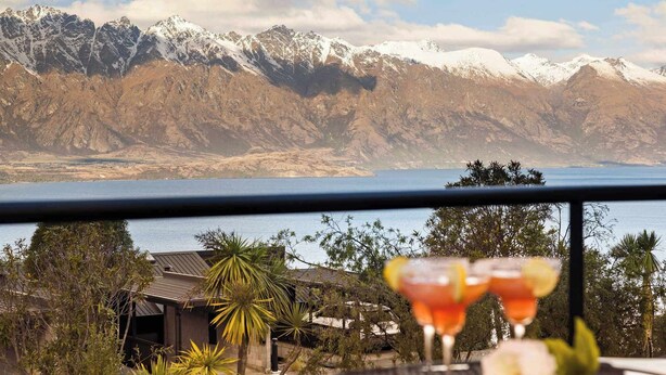 A balcony with a view of snow-capped mountains and a body of water.