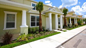 A row of townhouses with white columns, green lawns, and palm trees. - 17517 Dream (Clermont)