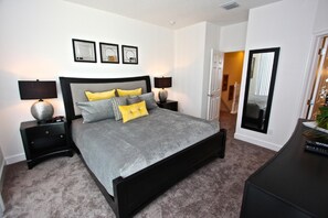 A bedroom with a bed, two bedside tables with lamps, a mirror, and framed pictures on the wall. - 17517 Dream (Clermont)