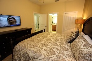 A bedroom with a bed, a TV, a dresser, and a door leading to a bathroom. - 1484 Champions Gate (Davenport)
