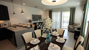A modern dining area with a glass table, white chairs, and a vase of white flowers. - 17521 Dream (Clermont)